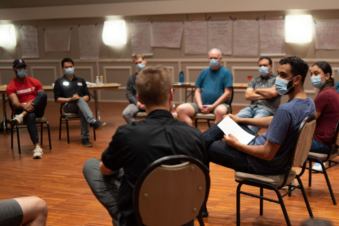 Eight participants in a circle, engaged in discussion during a first aid training course.